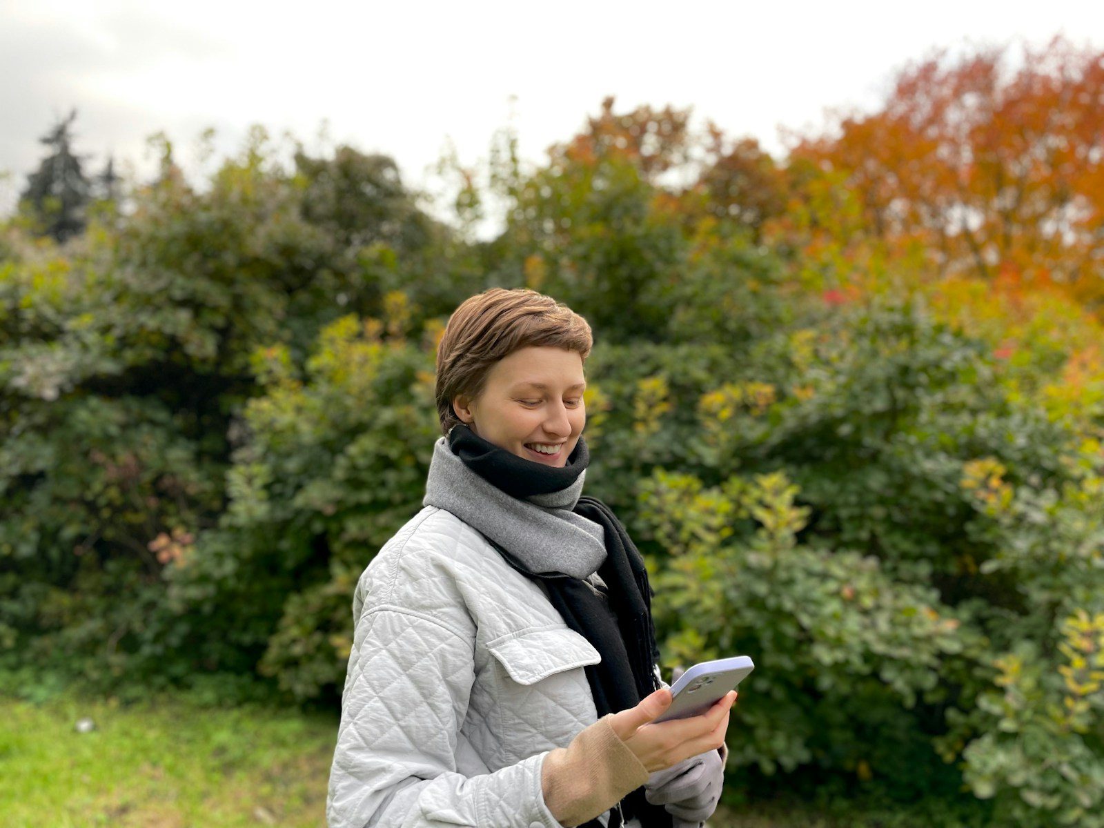 a woman standing in a field looking at her cell phone